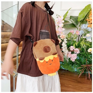 Close-up of a Capybara plush crossbody bag worn by a model against a warm floral background