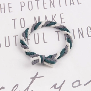 Close-up of handmade braided elastic hair tie in green, grey, and white on a card