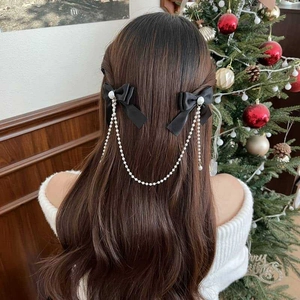 Detail of girls' black bow hair clip with white pearl tassels worn in a festive setting