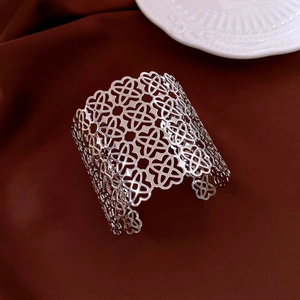 Detail view of silver hollowed four-leaf clover pattern on a wide open cuff bracelet