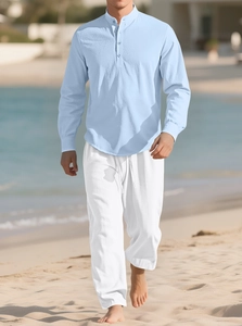 Men's light blue cotton linen Henley shirt and white drawstring trousers on a beach