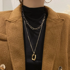 Detail of golden double-layer geometric necklace worn on a black turtleneck sweater