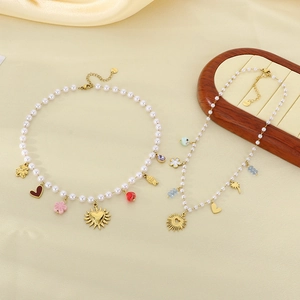 Detail of gold-plated pearl necklaces with heart, fish, and flower charms on satin