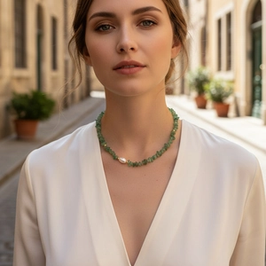 Detail of green stone beaded necklace featuring a baroque pearl on a female neck
