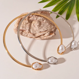 Minimalist gold and silver torque chokers with baroque pearls on a natural rock