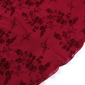 Détail du tissu en maille florale avec base bordeaux et motifs de fleurs noires