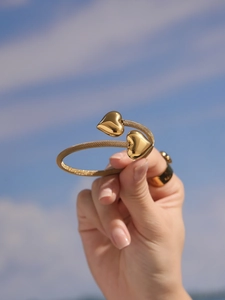 Detail of gold hollow heart bangle with mesh textured band and mirror polished finish