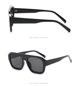 Detail view of large square black sunglasses with thick frames and dark grey lenses