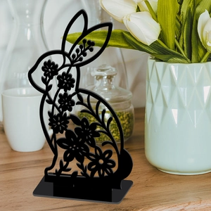 Detail of a black hollow rabbit sculpture on a wooden desk with spring floral decor