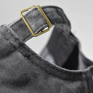 Detailed macro view of washed cotton fabric and adjustable vintage brass buckle on baseball cap