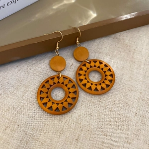 Detailed view of vintage hollow sun-shaped wooden earrings on rustic linen background