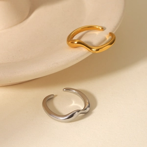 Minimalist wave open rings in gold and silver finish on a cream textured vessel