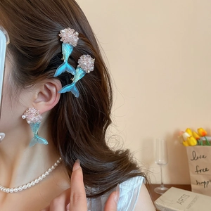 Detail view of gradient blue mermaid tail hair clips and earrings with pink pearls
