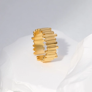 Detail showing gold-plated geometric striped ring on a white stone decorative display