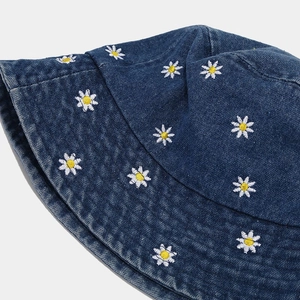 Dettaglio del ricamo a margherita sul tessuto denim blu scuro vintage del cappello pescatore