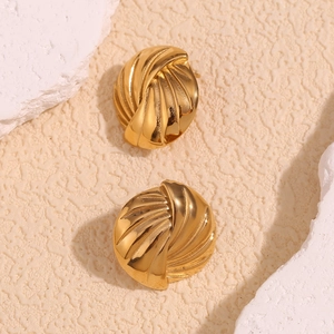 Dettaglio dei orecchini vintage dorati con eleganti motivi a spirale e trama intrecciata