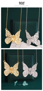 Detailed view of butterfly pendant necklaces in gold and silver finish with textured wings