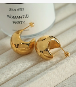 Macro shot of chunky gold bean earrings with a high-polished metallic finish on a display