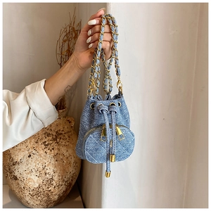 Detail of blue denim mini bucket bag with quilted pocket and woven chain strap