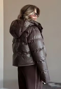 Detail view of glossy dark brown puffer jacket with hood and reversible padded material