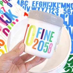 Detail of waterproof vinyl letter stickers applied to a white cup with water droplet texture