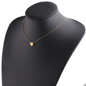 Detail of a gold puzzle piece pendant on a slim chain displayed on a black bust model