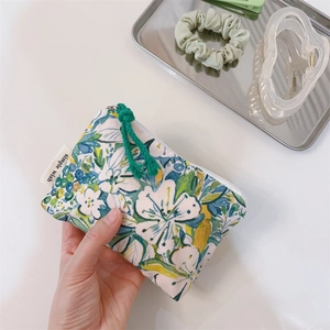 Close-up of floral cotton pouch with zipper and simple wish label held by hand