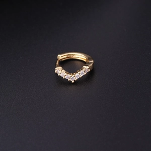 Minimalist V-shaped gold hoop earring with sparkling zircon stones on black background