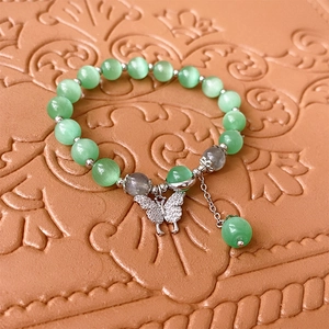 Détail des perles oeil de chat vertes et du pendentif papillon sur le bracelet
