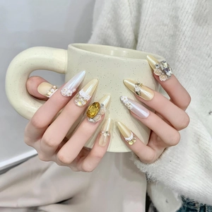 Detailed view of handmade luxury gold press-on nails with intricate rhinestone and floral accents