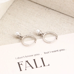 Macro detail of S925 silver hoop earrings featuring elegant white pearl pendants