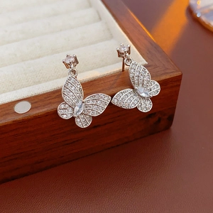 Close-up of butterfly stud earrings with zircon stones on beige velvet jewelry box