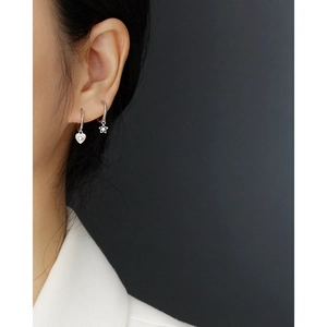 Close-up of asymmetric s925 silver star and heart drop earrings on female model