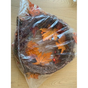 Detail of autumn wreath with maple leaves and berries in clear plastic packaging