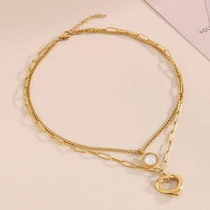 Dettaglio della collana a doppio strato dorata con catena a graffetta e ciondolo a cuore