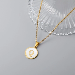 Detail of 18K gold stainless steel necklace with white shell pendant engraved with letter Q