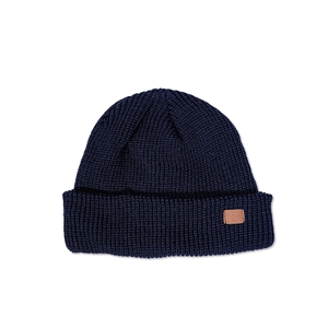 Close-up of navy blue knit beanie with waffle texture and brown leather patch detail