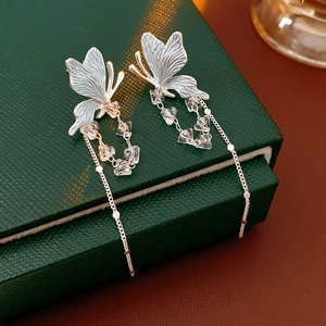 Détail de boucles d'oreilles papillon argentées avec perles cristal et pompons