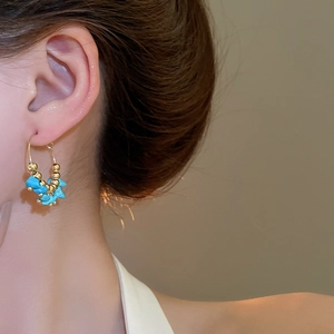 Detailed close-up of bohemian gold hoop earrings with turquoise stones worn by a model