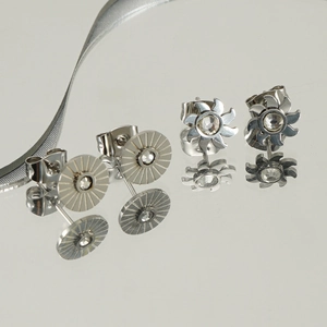 Minimalist stainless steel stud earrings with star and flower designs on mirror reflection