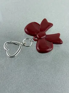 Close-up of red resin bow keychain with silver heart-shaped lobster clasp on grey felt