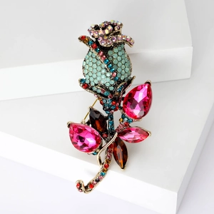 Detail of vintage rose brooch with red crystals and turquoise rhinestones on gold metal