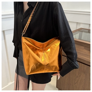 Detailed view of metallic gold tote bag with stylish chain strap on model