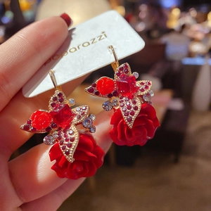 Détail de boucles d'oreilles vintage avec rose rouge, cristaux et nœud papillon chic
