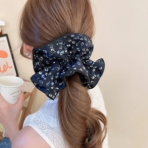 Detail of floral fabric double-layered scrunchie bow tied on a ponytail in cozy setting