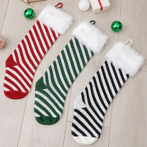 Three striped knitted Christmas stockings in red, green, and black with white faux fur trim