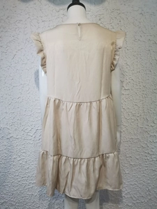 Detail of beige sleeveless dress featuring a ruffle hem and satin finish texture