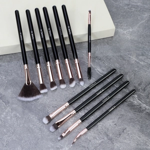 Macro shot of 11-piece black and rose gold makeup brushes on marble surface
