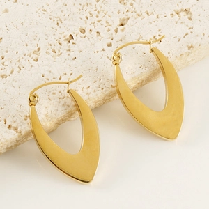 Polished gold U-shaped chunky stainless steel earrings on a textured stone surface