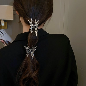 Detail of silver liquid metal butterfly hair clips styled on a woman's ponytail back view